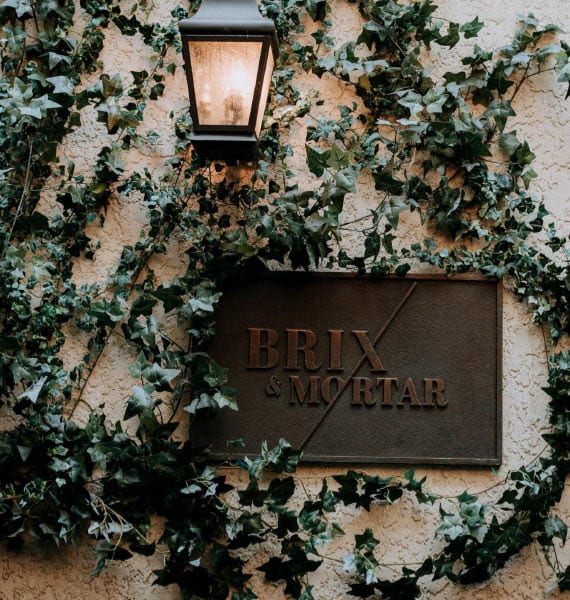 The quaint exterior of Brix & Mortar adorned with ivy and a glowing lantern, inviting guests to a unique wedding experience in Vancouver