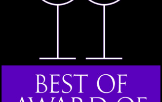 An image displaying the 'Wine Spectator Best of Award of Excellence 2023' in bold white and purple text, with a graphic of two stylized wine glasses above the title, signifying high recognition in the wine industry and award gained by Brix & Mortar restaurant.